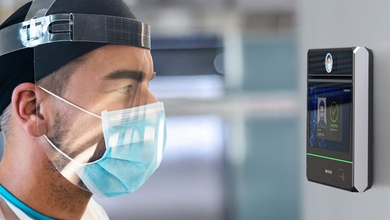 Man in PPE using an iris recognition device.