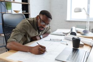Consultant working on a blueprint at his desk